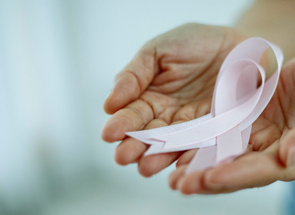 Hands handing a breast cancer ribbon